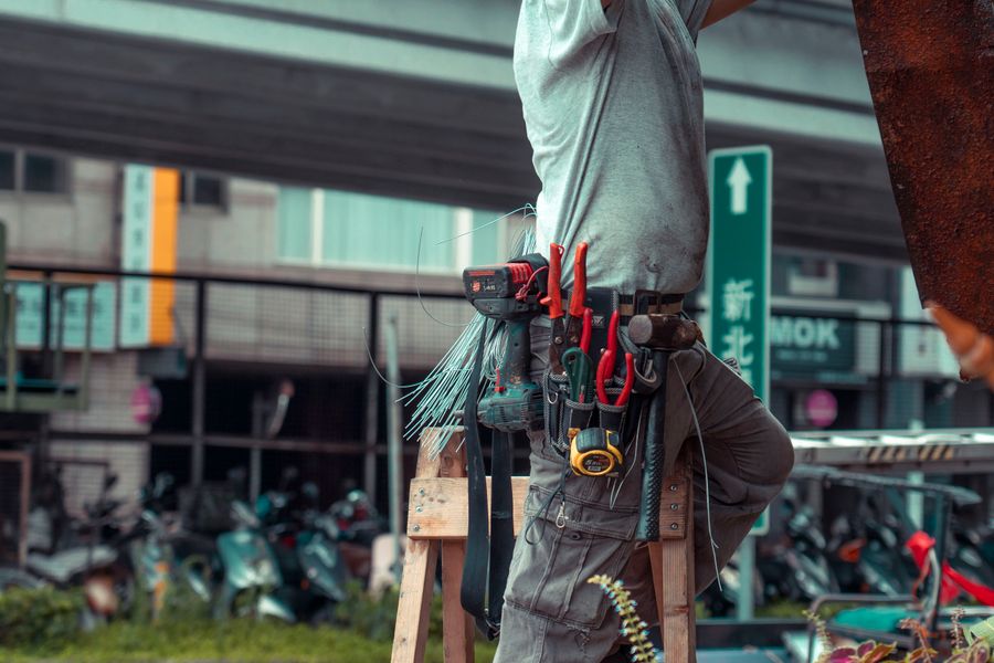 Handyman with tool belt working on a ladder