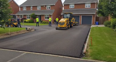 Completed local service project — fresh paved driveway with crew on site