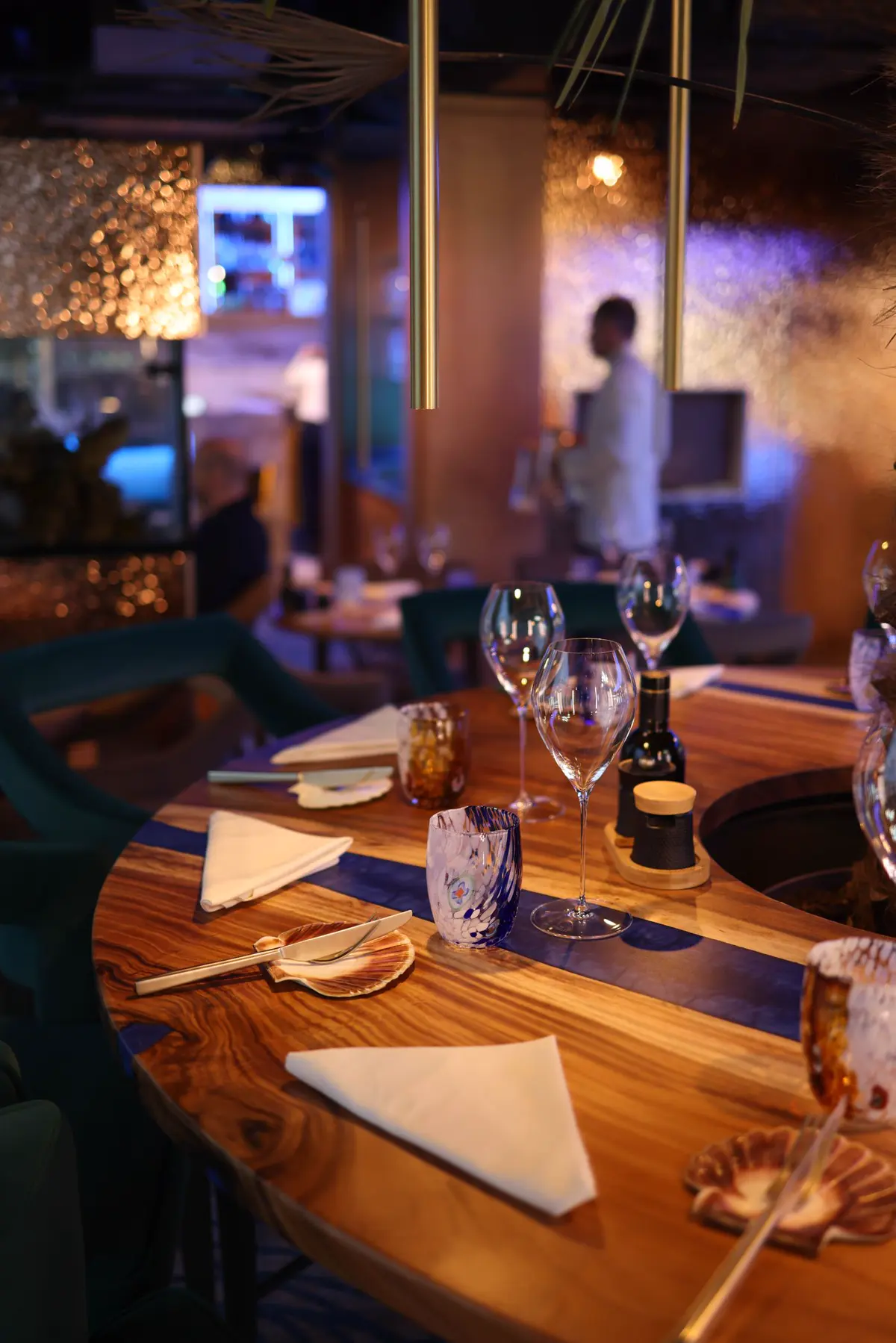 Warmly lit fine-dining room with set tables, wine glasses and ambient lighting