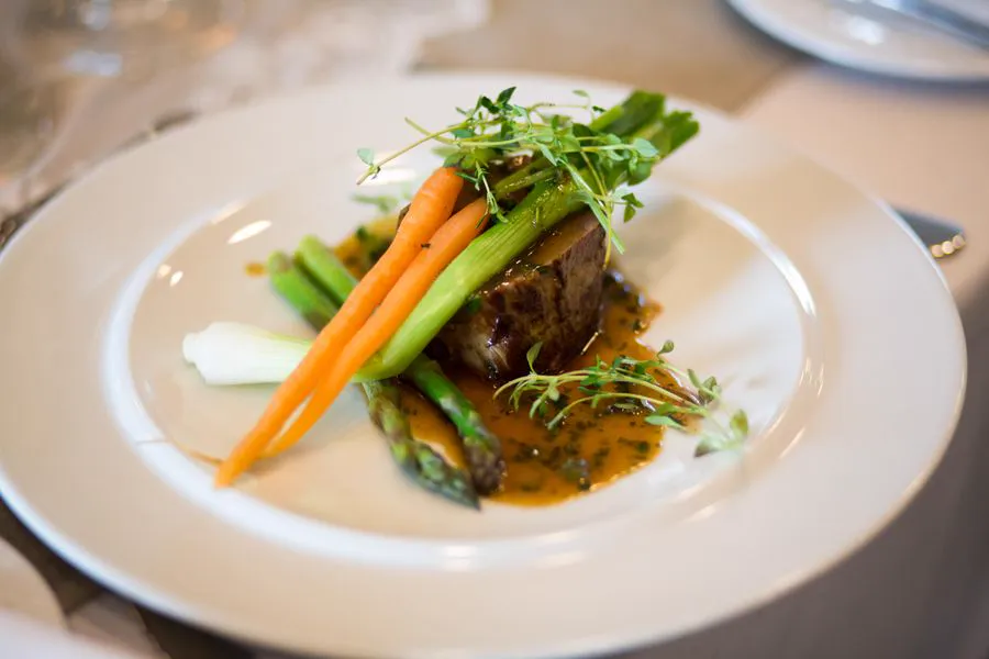 Gourmet plated main course with seared beef, baby vegetables and jus